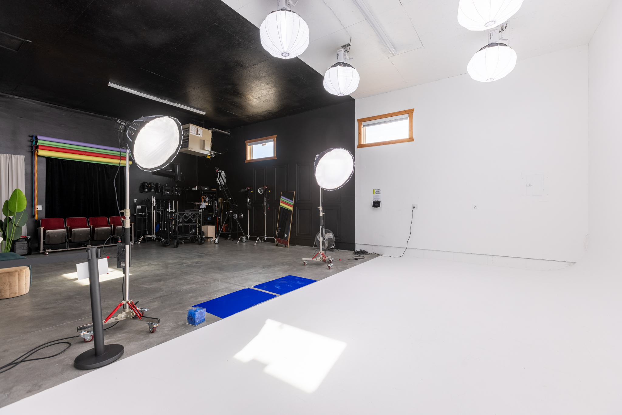 Professional photo and video studio rental in Idaho Falls at Film Garage, featuring a large white cyclorama wall, studio lighting, black walls, and photography backdrops.
